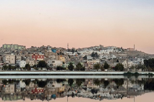 Beautiful cityscape reflected in a lake with a serene sunset sky above.