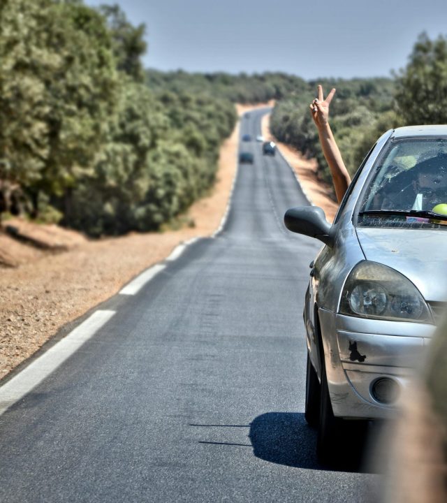 A car journey through scenic Ifrane, Morocco, with a playful peace sign gesture.