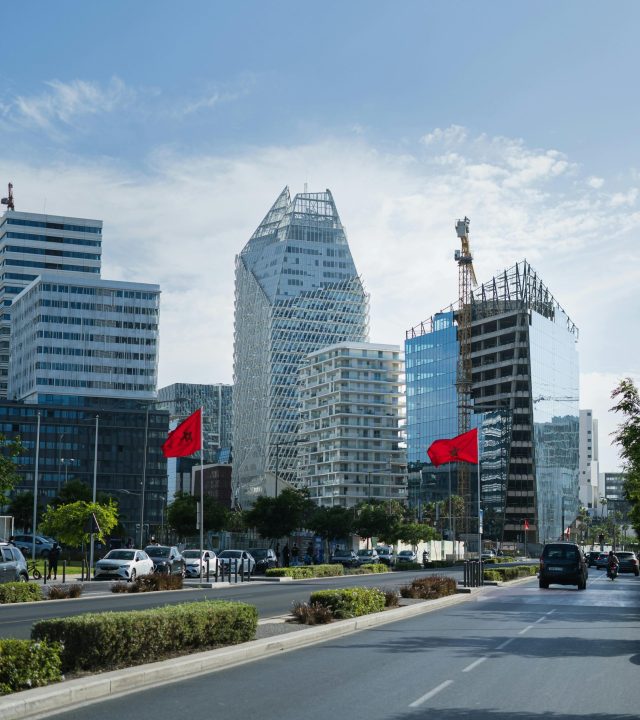 Urban skyline of Casablanca featuring modern architecture and Moroccan flags on a sunny day.
