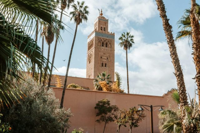 View of the Koutoubia Mosque tower surrounded by lush gardens in Marrakech, Morocco.
