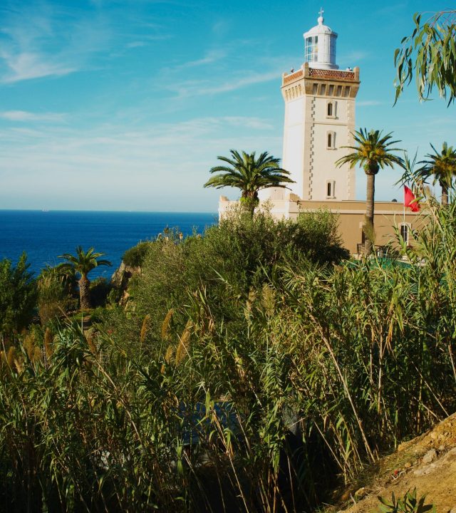 Captivating view of Cape Spartel Lighthouse amidst lush greenery and ocean in Morocco.