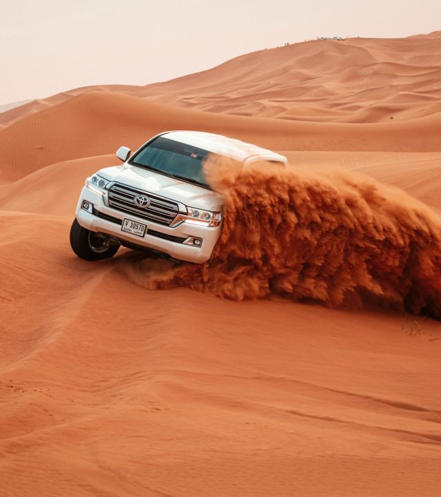 A Toyota Land Cruiser drives through the vast sandy dunes on an exciting off-road adventure.